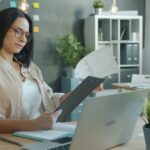 Professional reviewing financial documents and a laptop when checking card charges