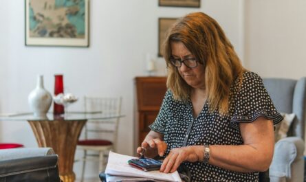 Person using a calculator to review bank statements and savings account fees
