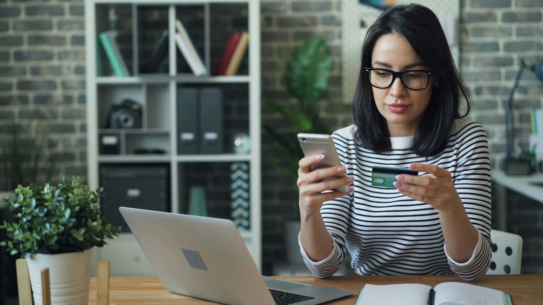 Woman checking a digital payment status on a smartphone with a bank card